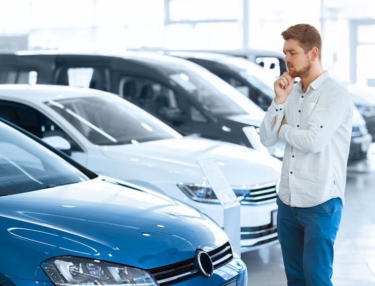 un hombre delante de una fila de coches aparcados