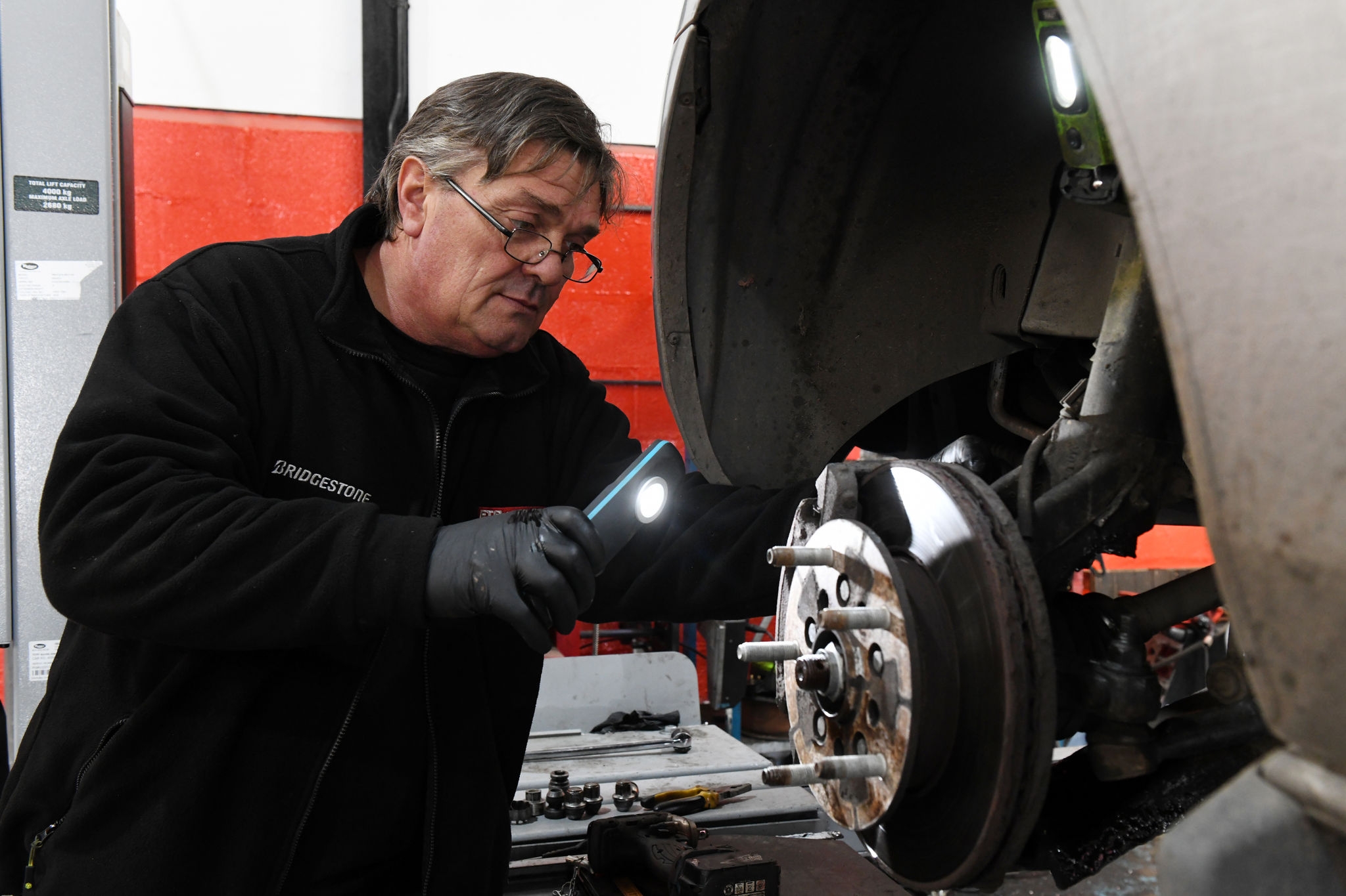 Mecánico revisa frenos de coche en taller