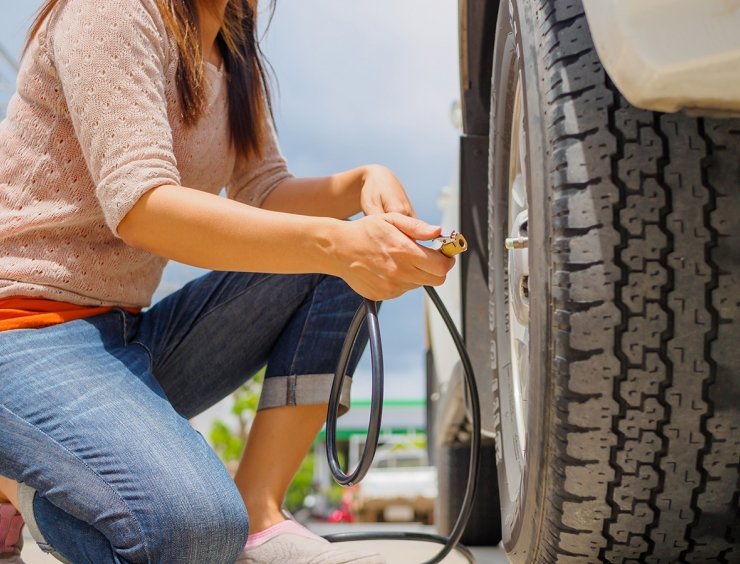una mujer comprueba la presión de los neumáticos