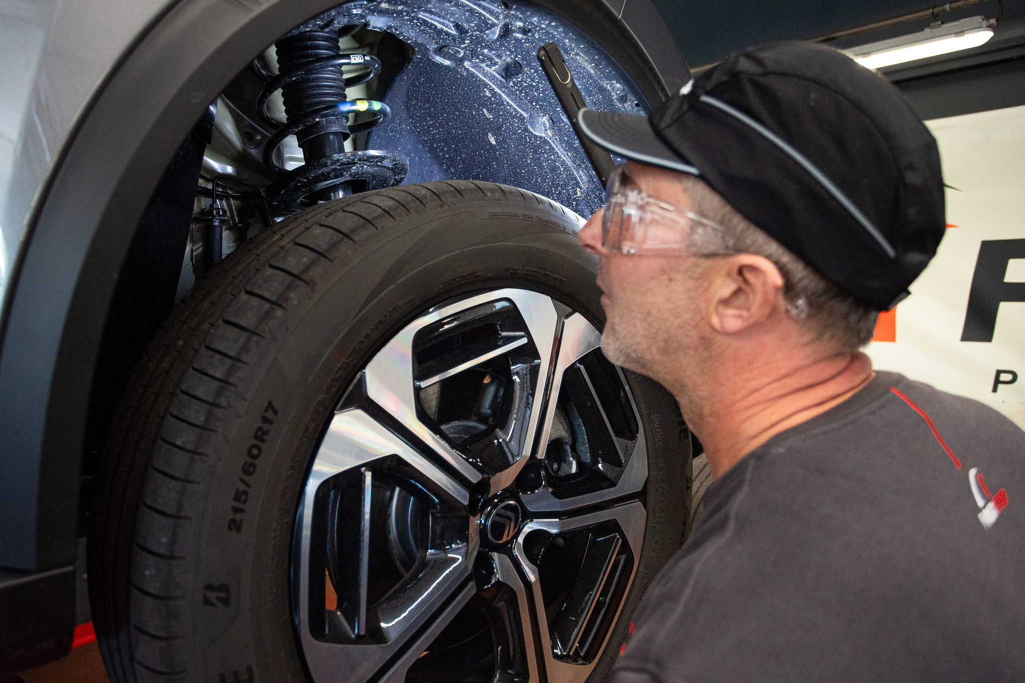 Mecánico inspecciona suspensión y rueda del coche 